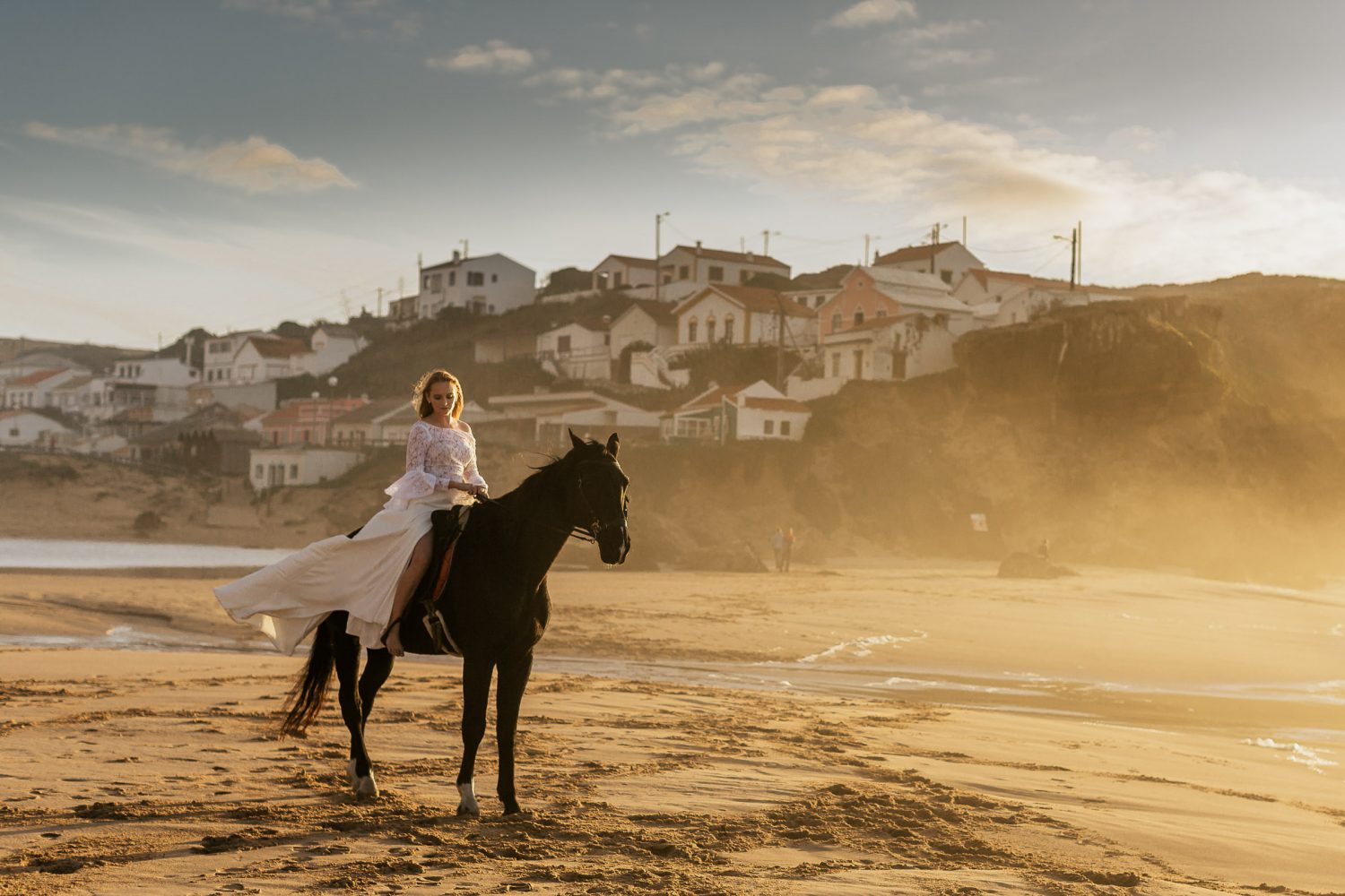 Bride on a black horse at sunset on a beach